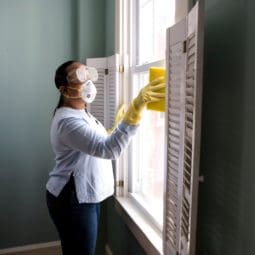 woman cleaning the window with the mask