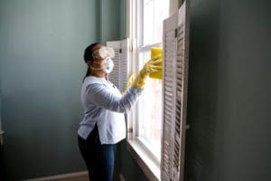 woman cleaning the window with the mask