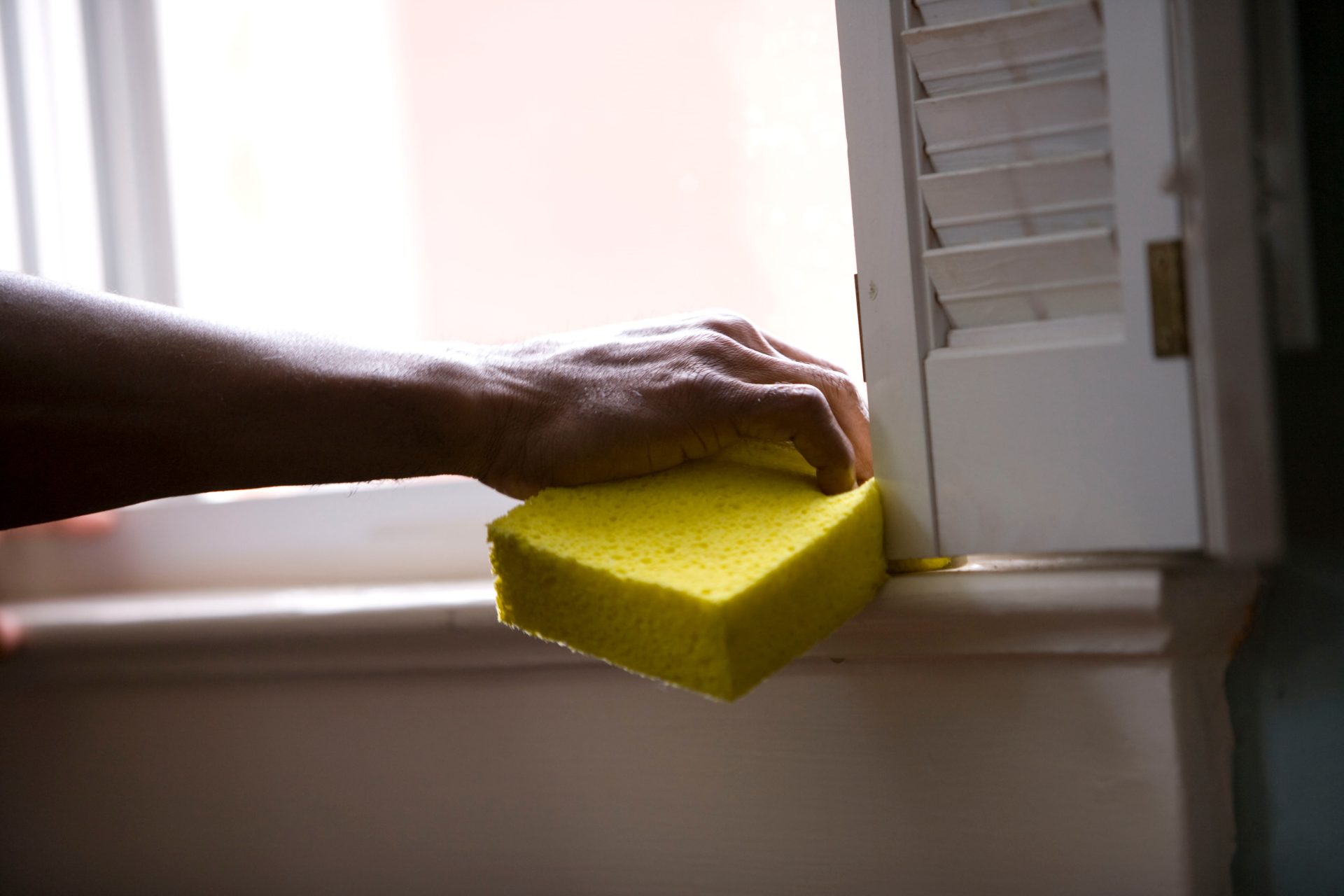 cleaning window with yellow sponge